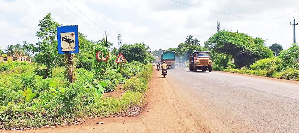 Directional sign on Belgaum-Sambara road in thicket of bushes